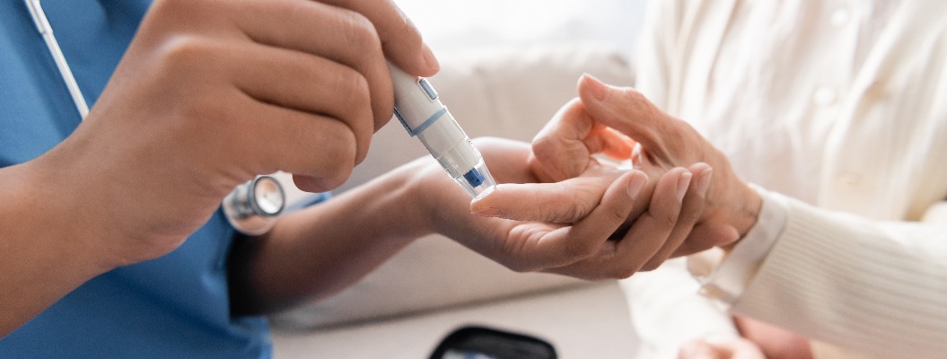 Ausschnitt einer multiethnischen Krankenschwester, die einer älteren Frau mit einer Lanzette Blut abnimmt.