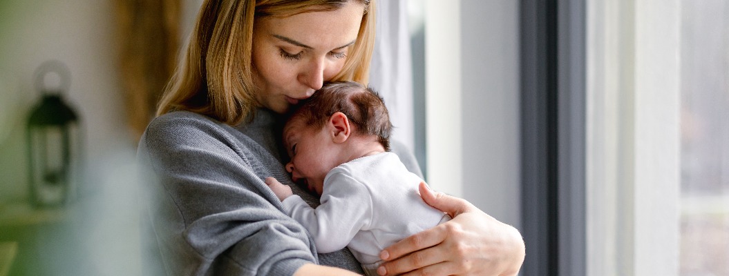 Eine liebevolle Mutter umarmt ihr kleines Baby zu Hause.