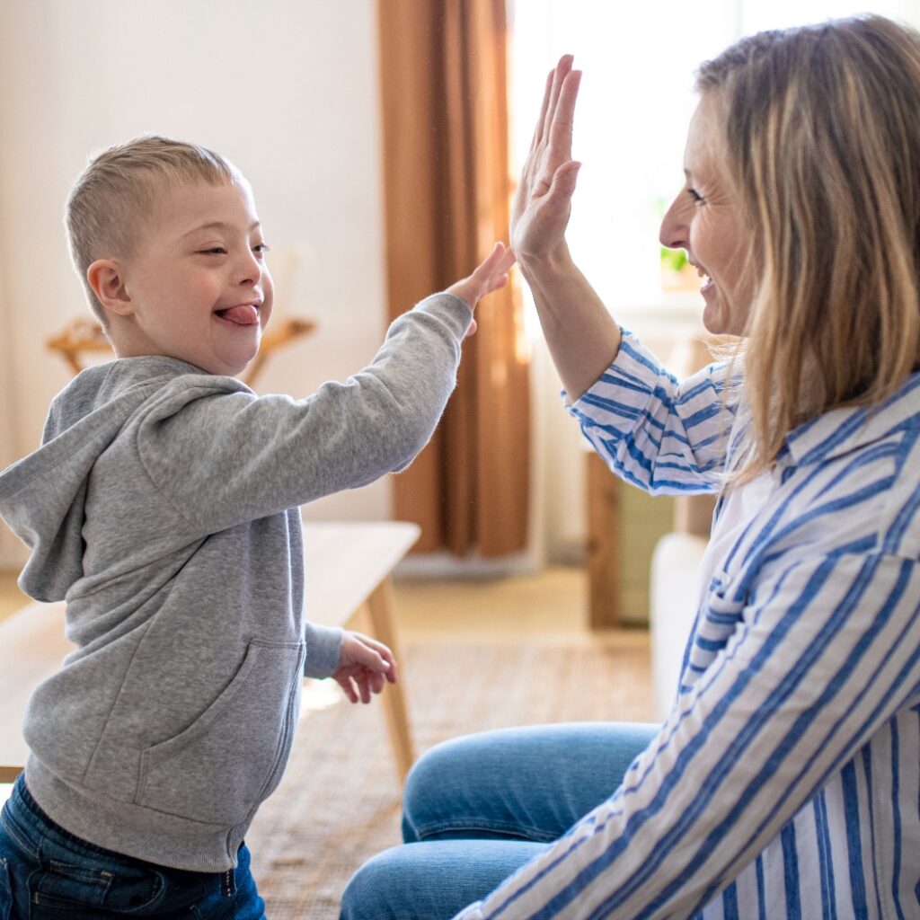 Alleinerziehende Mutter spielt zu Hause mit ihrem Kind mit Down-Syndrom.