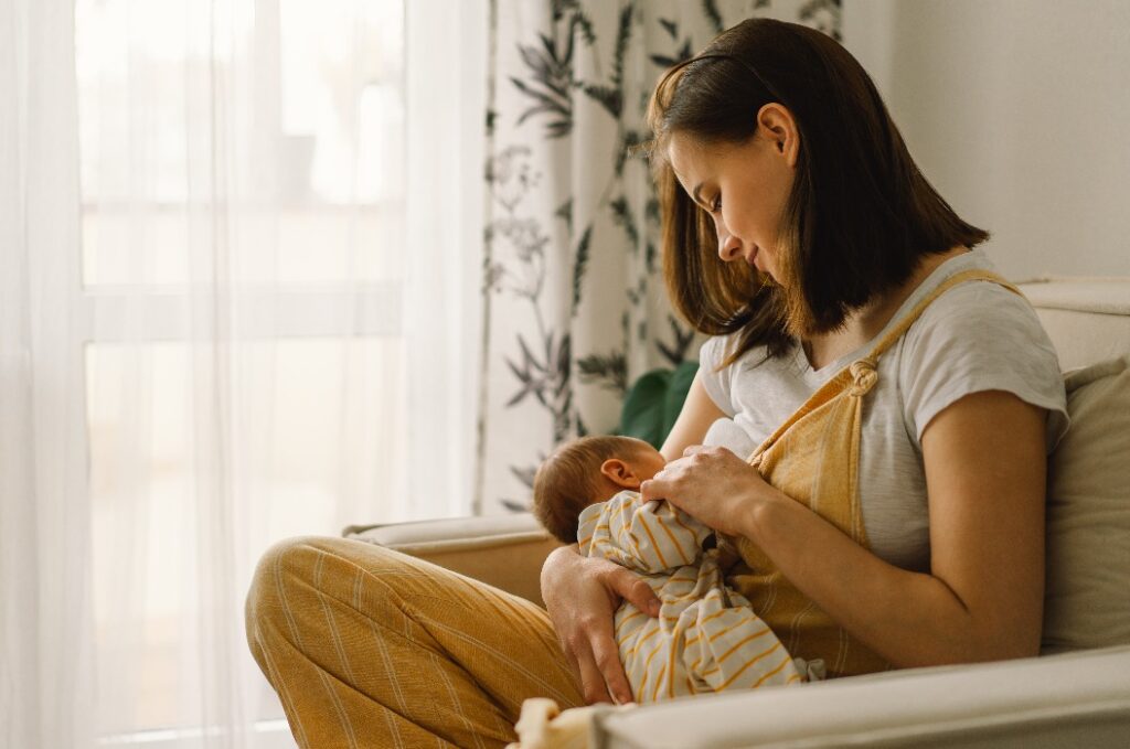 Ein neugeborener Junge trinkt Milch an der Brust seiner Mutter. Porträt der Mutter und ihres stillenden Babys.