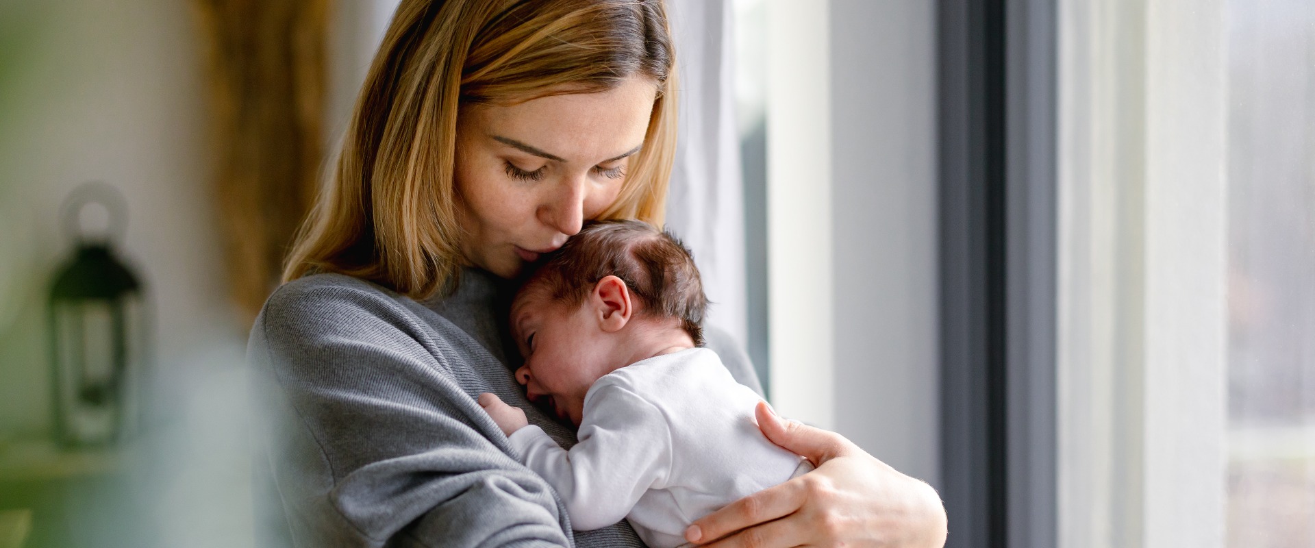 Eine liebevolle Mutter umarmt ihr kleines Baby zu Hause