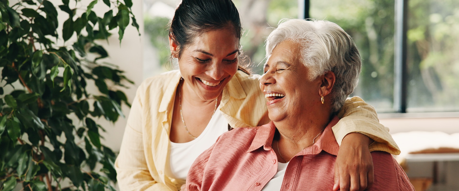 Lachen: Eine ältere Mutter und eine Frau zu Hause mit einem Lächeln, Liebe oder einer Umarmung im Wohnzimmer. Lustig: Eine ältere Mutter und ihre erwachsene Tochter mit einer glücklichen Familie, Verbundenheit und einer Umarmung mit der Mutter am Muttertag