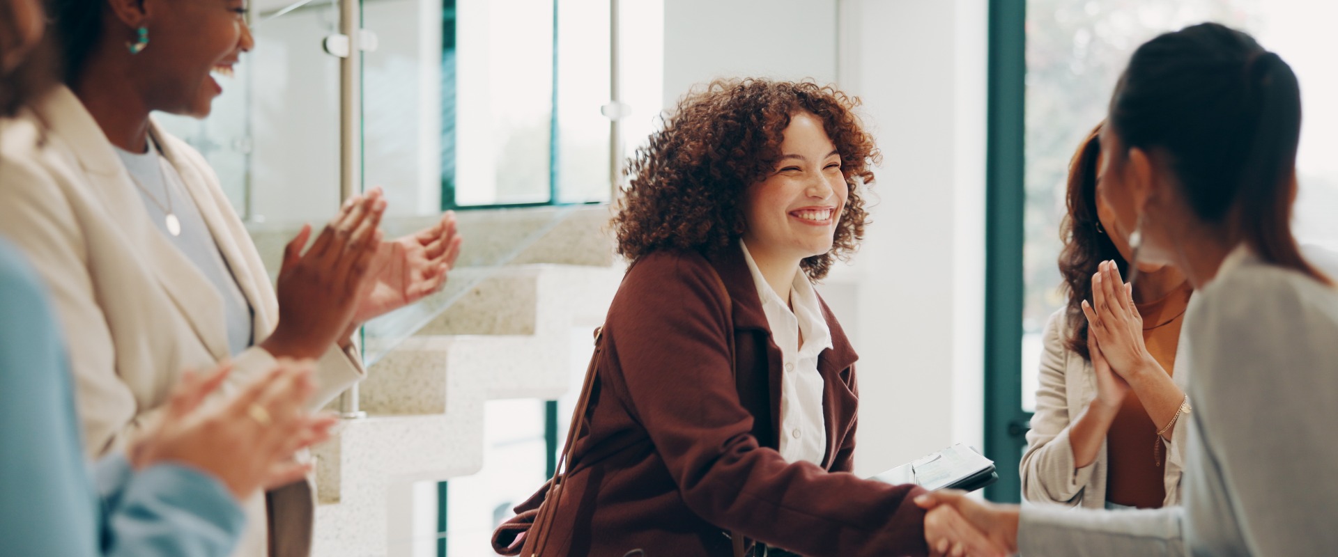Mitarbeiter, Frauen und glückliche Gesichter im Büro bei einem Händedruck anlässlich der Einstellung, der Begrüßung und der Vertragsunterzeichnung. Geschäftsleute, Menschen und ein Lächeln oder Applaus für geleistete Arbeit, Beförderung und Karrierechancen bei einer Besprechung